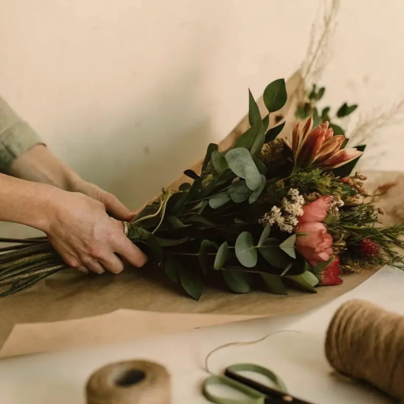 Hands tying a bouquet of roses with twine