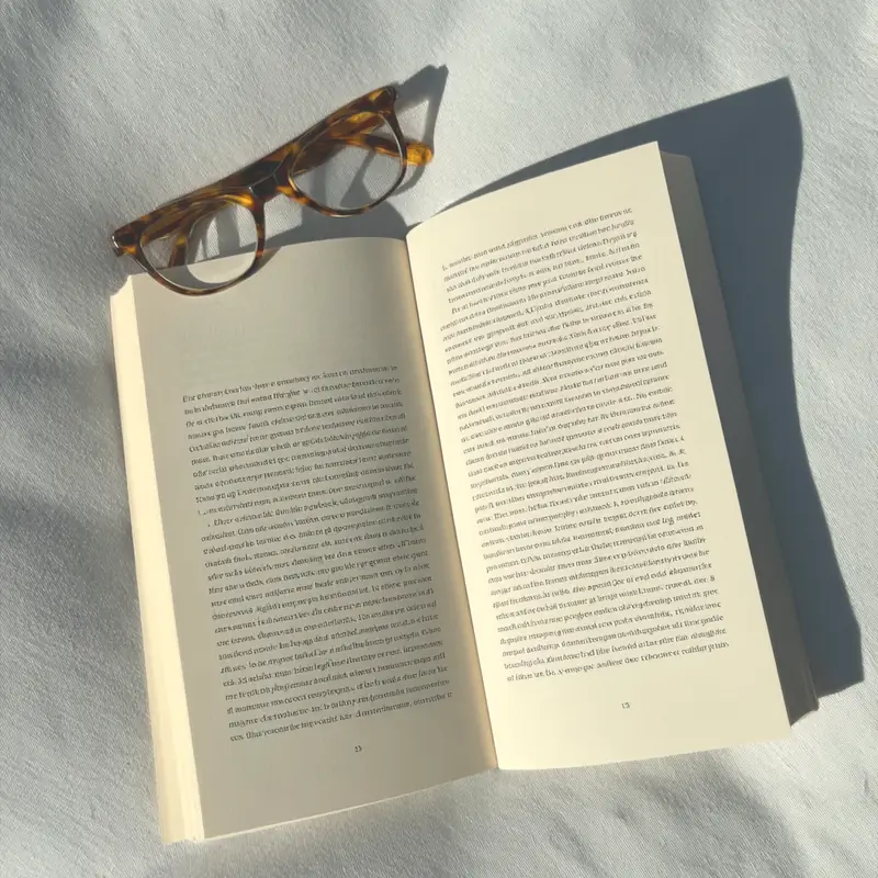 An open book with glasses resting on it